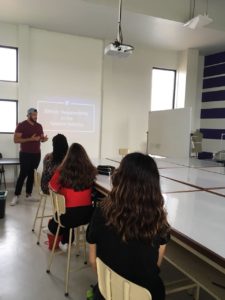 Young male SUNY Ulster student speaking at the front of a classroom during a presentation. 