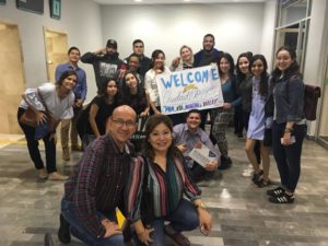 Group of students and staff posed holding "Welcome Sign" for SUNY Ulster students arriving at airport in Mexico. 
