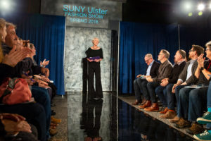 Kristin Flynn stands at the end of the fashion shows runway as the crowd looks on! 