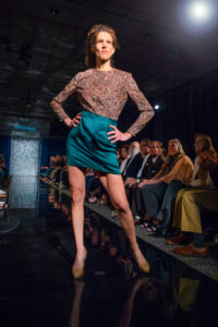 A model poses at the end of the runway with a small grin on her face. 