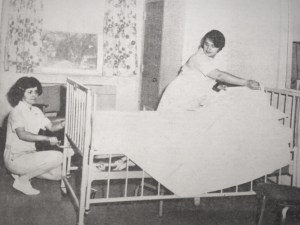 Vintage photo of two nursing students making a hospital bed. 