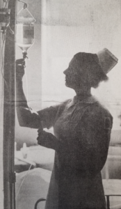 Silhouette photo of nurse checking fluid bag in hospital setting. 