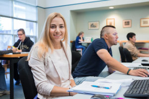 Young sophisticated woman smiling while studying in the library. 