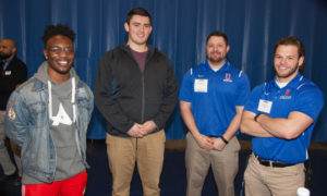 Four athletic young men standing together smiling. 