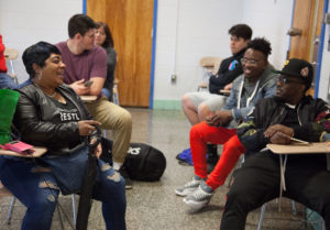 Photo of students having a conversation while sitting in a class room.