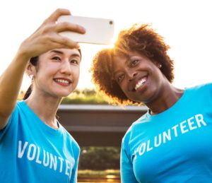 Two women pose together for a photo wearing shirt that read "Volunteer" .