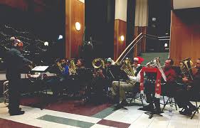 Professors and staff of SUNY Ulster sit with instruments and christmas hats on at last years Tuba Christmas show