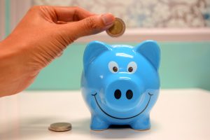 Hand about to insert coin into blue piggybank