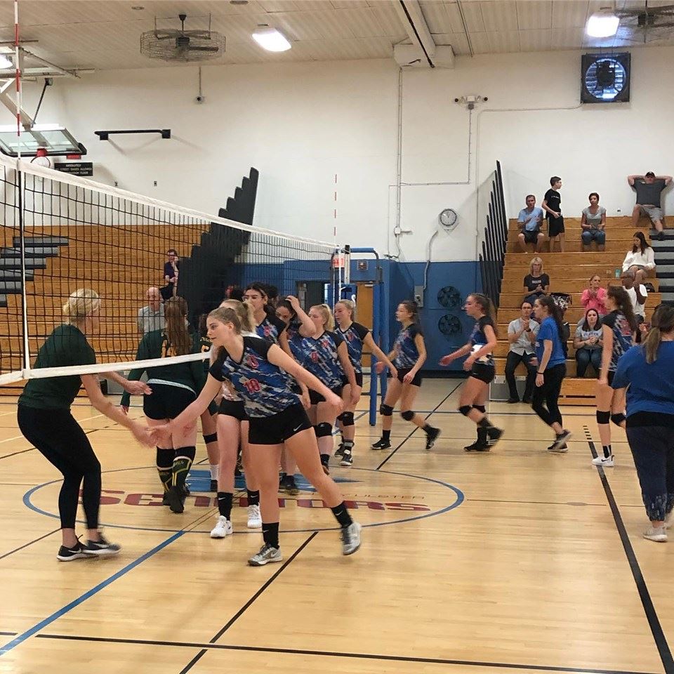 Girls on a gym court give high fives after a volley ball game