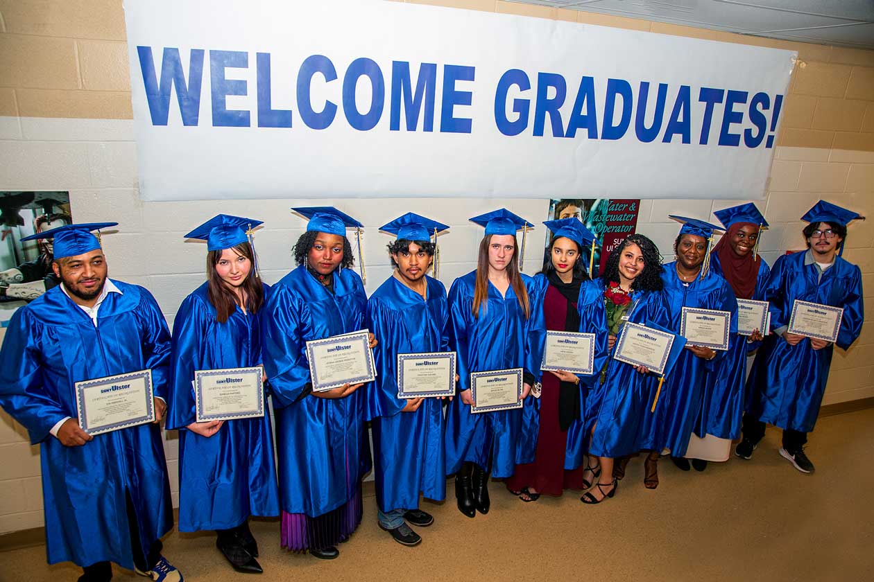 Welcome Graduates banner with graduates holding diplomas.
