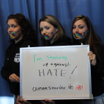 students holding no h8 whiteboard with tape over mouth