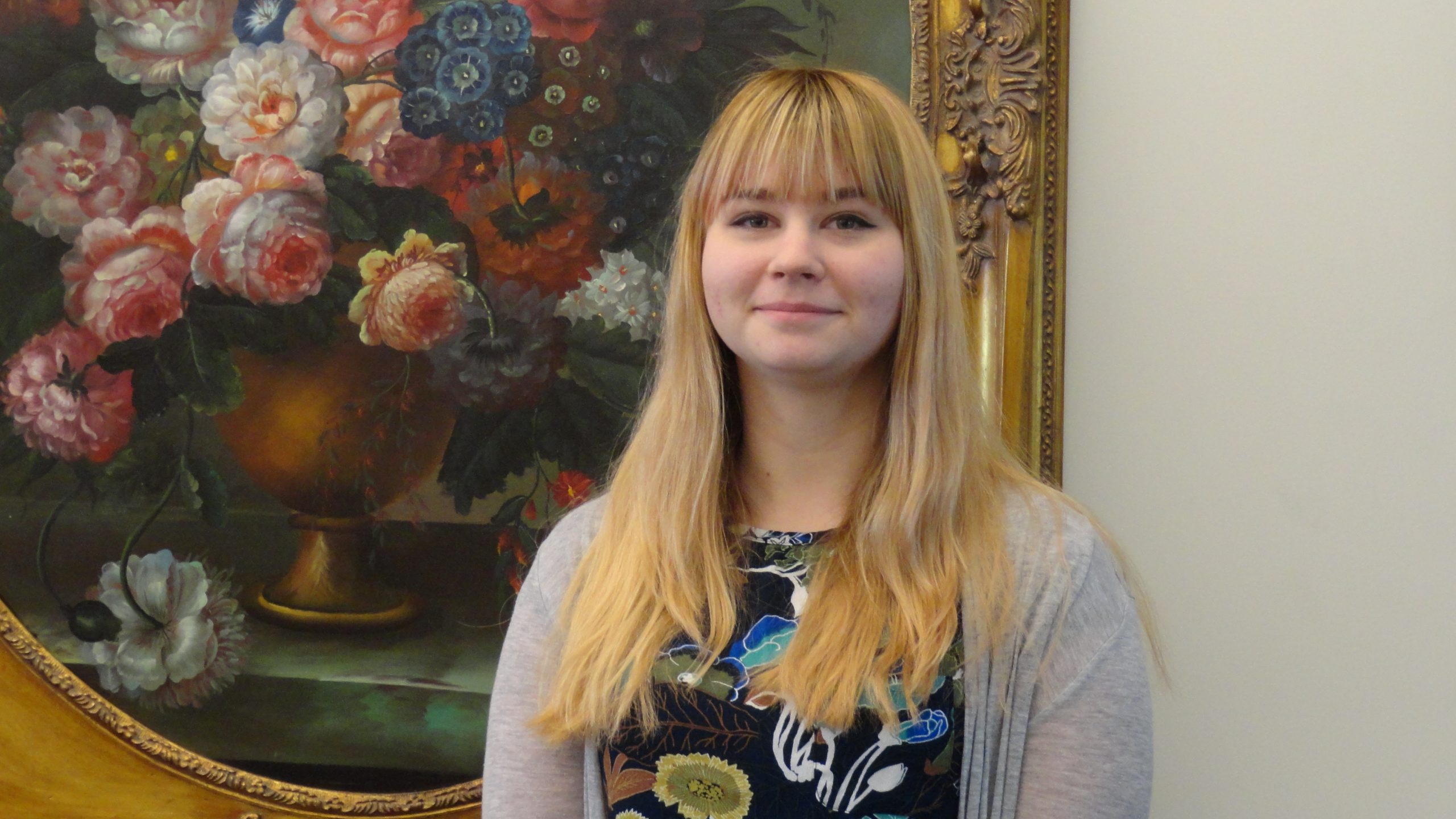 Chelsea Stingel standing in front of painting of flowers
