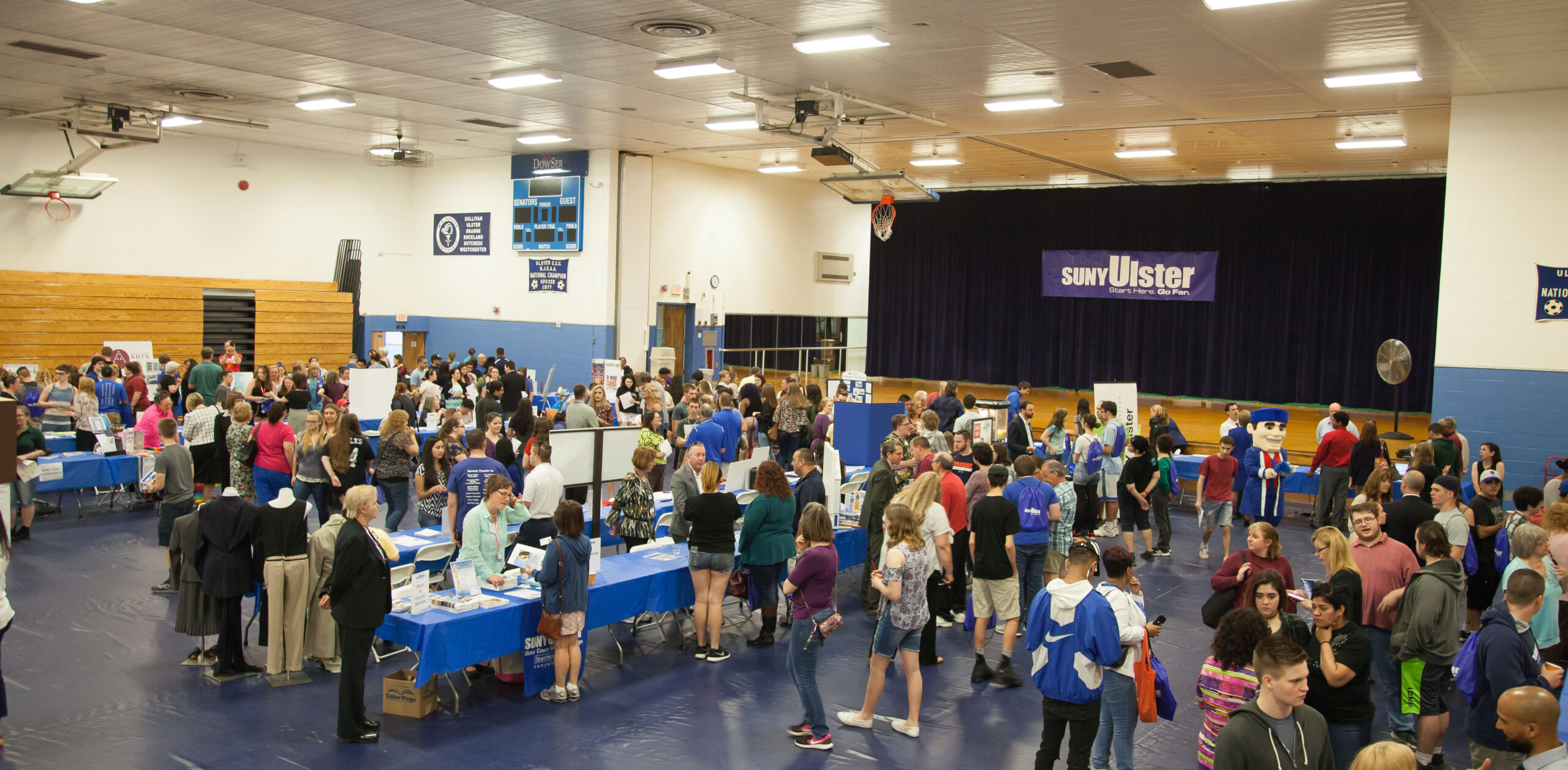 People walking around tables in the gym for open house