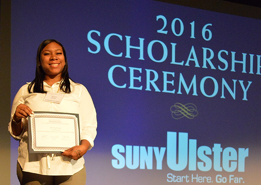 Woman at the 2016 SUNY Ulster scholarship ceremony holding her award and smiling