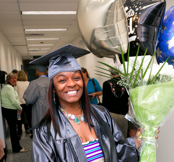 Graduate smiling and holding balloons at graduation