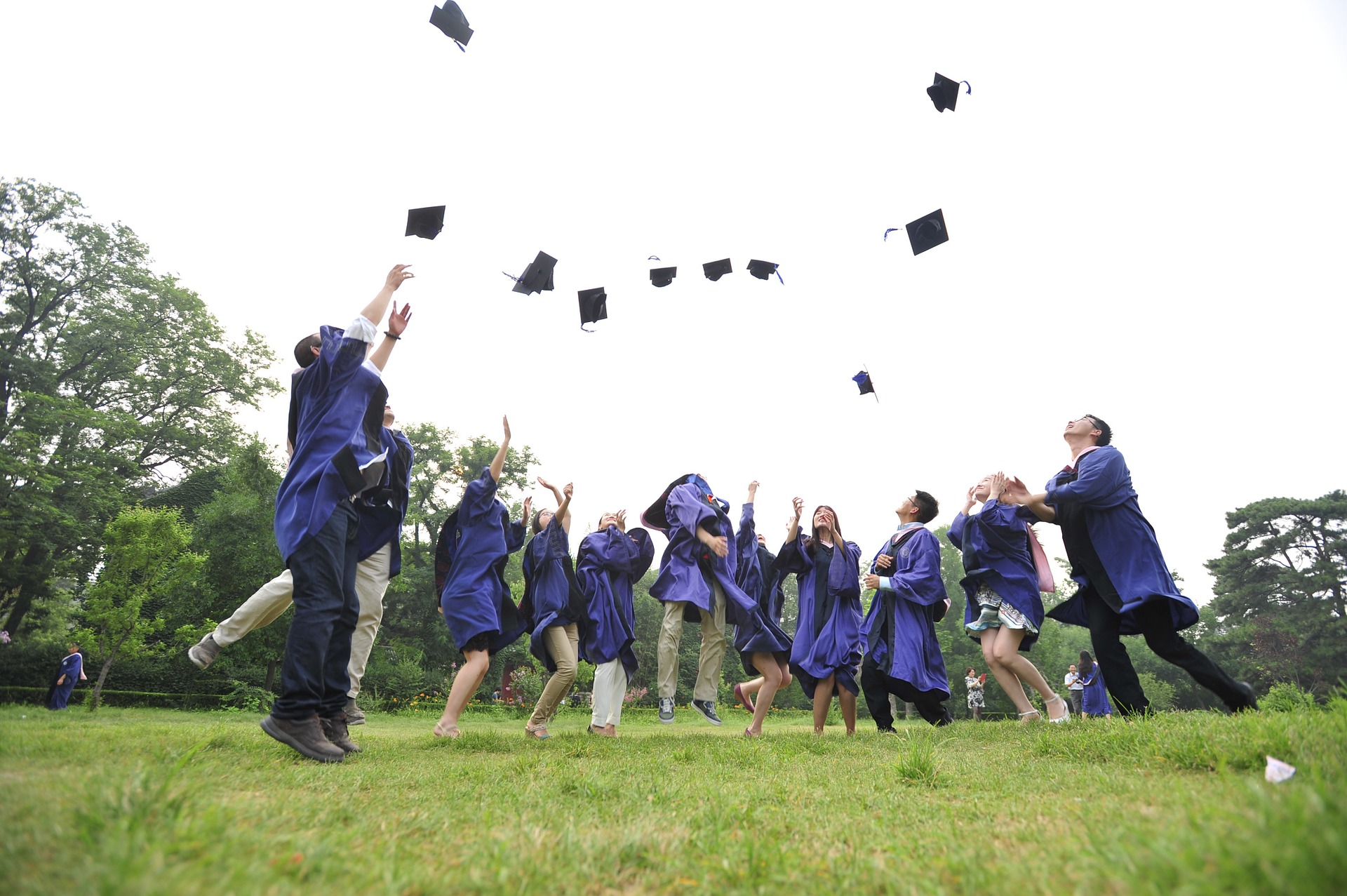Graduates throwing hats into the air on a field