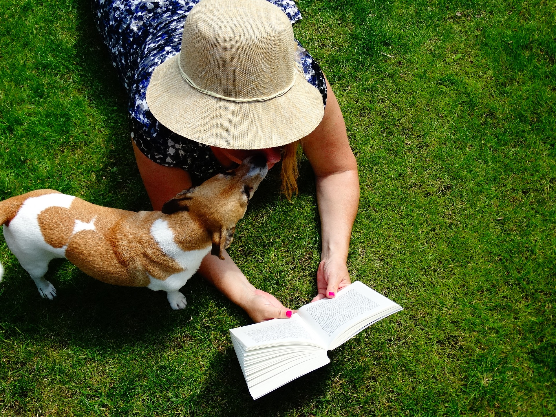 Woman reading a book while dog is nearby