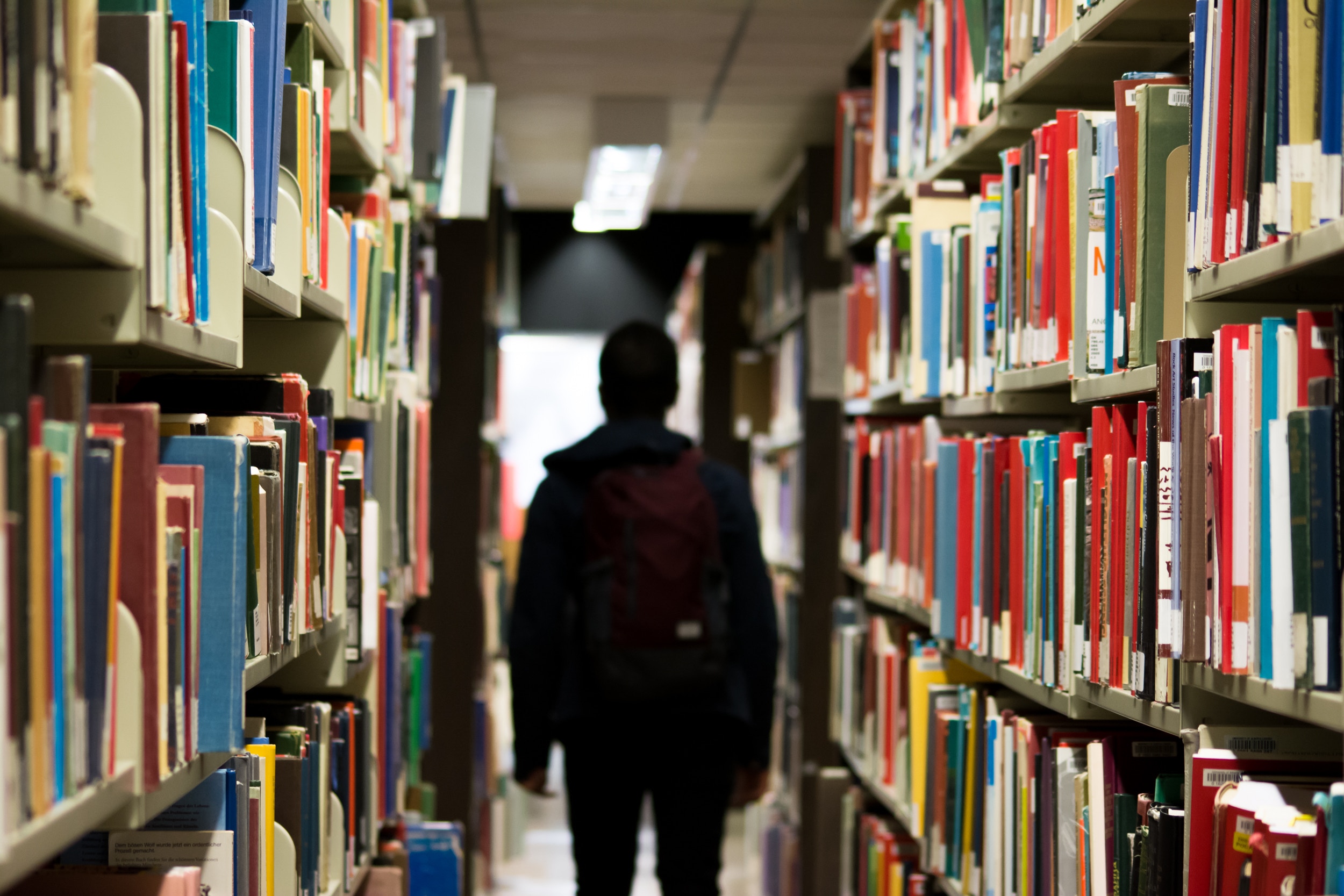 figure of male walking among library stacks