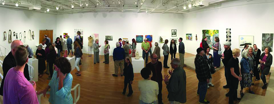 art gallery wide view with many people talking in small groups