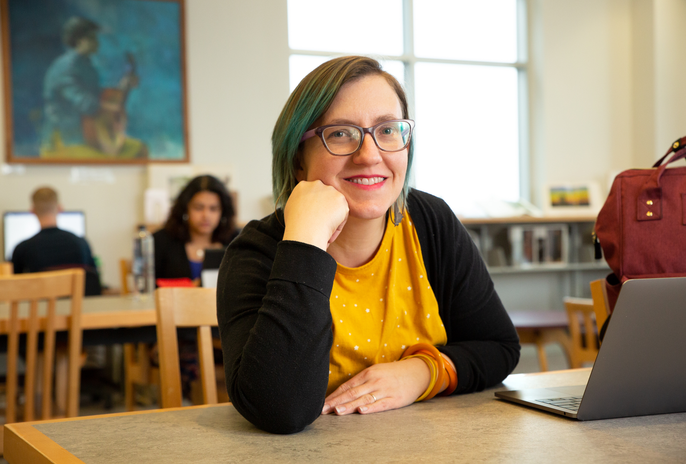 Adult student sitting in library with laptop