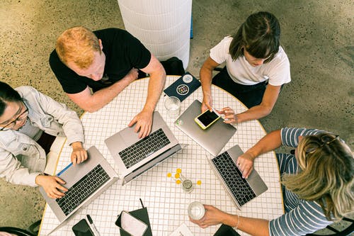 group of students with laptops sitting around a table.