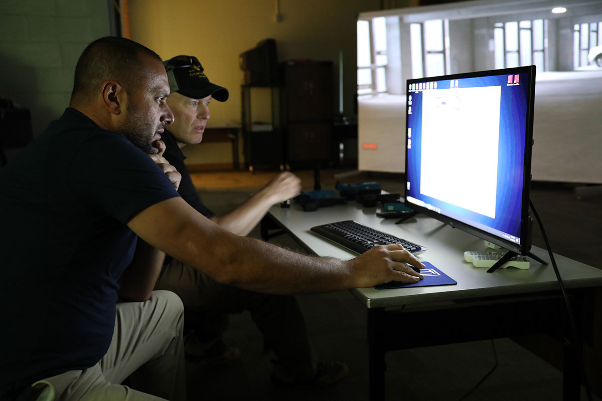 CRJ police student and instructor by a computer