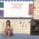 photograph of girl sitting against a wall